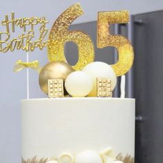 a white cake with gold decorations on top and the number fifty five candle in the middle