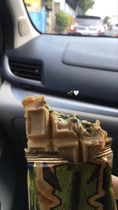 a person holding up a cup filled with food in the back seat of a car