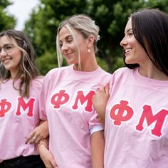 three women wearing pink shirts with the word mom on them