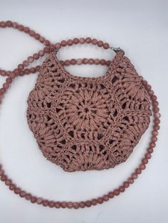 a pink crocheted purse on a beaded necklace