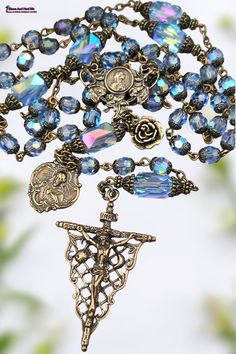 One of the kind Blessed Virgin Mary Lilies, Sacred Heart of Jesus, St Therese Solid Bronze Medals Antique style Heirloom Rosary with Genuine Austrian Swarovski Blue Aquamarine Aurora Borealis Crystal. Medium Size Rosary. Handcrafted Rosaries are mostly larger than commercial rosaries, please see description for size reference.   Immerse yourself in celestial devotion with this one-of-a-kind antique-style heirloom rosary. Featuring handcrafted solid bronze medals of the Blessed Virgin Mary with l Celestial Bronze, The Blessed Virgin Mary, Queen Of Heaven, St Therese, Aurora Borealis Crystal, Heart Of Jesus