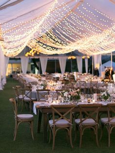 an outdoor tent with tables and chairs covered in lights