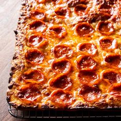 pepperoni pizza sitting on top of a metal rack next to a wooden tablecloth