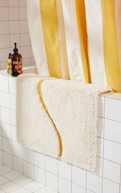 a towel rack in the corner of a bathroom with yellow and white striped curtains behind it