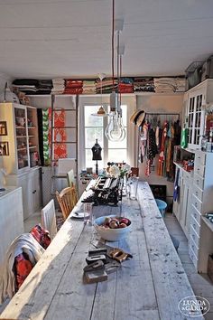 a long table in the middle of a room with lots of clutter on it