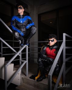 two men dressed as batman and robin wayne are sitting on the stairs in their costumes