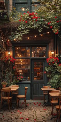 the outside of a restaurant with tables and chairs in front of an open door that has red flowers on it