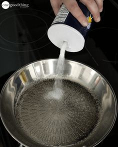 someone is pouring something into a large metal pan on the stove top with water in it