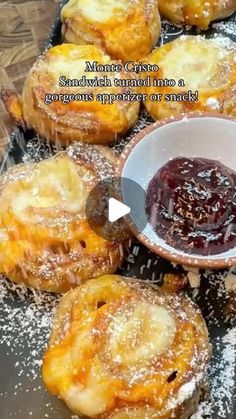 several pastries on a table with powdered sugar and jelly in a bowl next to them