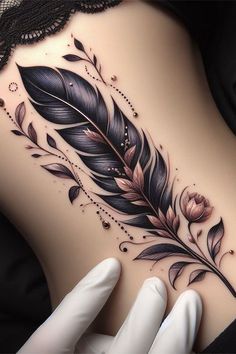 a woman's stomach has a tattoo with feathers and flowers on the side,