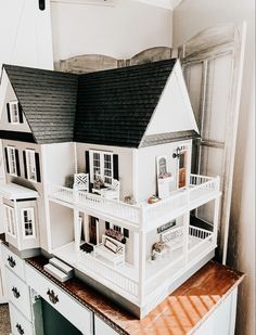 a white doll house sitting on top of a dresser