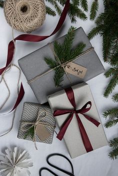 presents wrapped in grey and white paper, tied with red ribbon and twine on top of each other