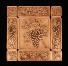 a tile with grapes on it and leaves around the edges is shown in this image