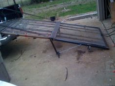 a metal bed frame sitting on top of a cement ground next to a truck parked in front of a building