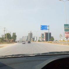 cars driving down the road in front of tall buildings and street signs on either side