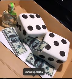 two dices sitting on top of each other with one dollar bill in front of them