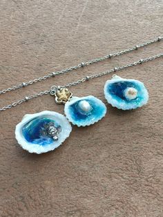 three seashells on a chain with a pearl in the center