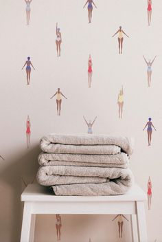 towels stacked on top of a white table in front of a wall with colorful images