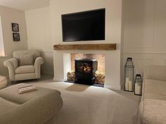 a living room filled with furniture and a flat screen tv mounted on the wall above a fire place