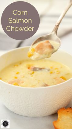 a bowl of corn and salmon chowder with a spoon full of soup in it