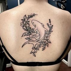 the back of a woman's shoulder with a dolphin and flowers tattoo on it