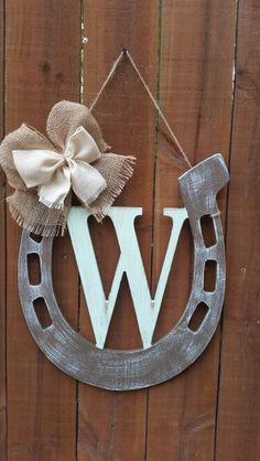 a wooden sign with the letter w hanging from it's side on a fence