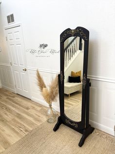 a large black mirror sitting on top of a wooden floor next to a white wall