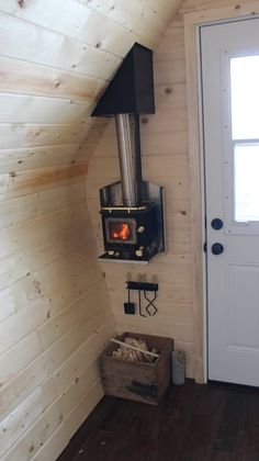 a wood burning stove mounted to the side of a wall in a room with wooden floors