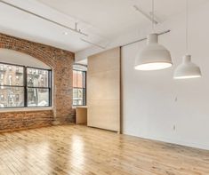 an empty room with wooden floors and brick walls