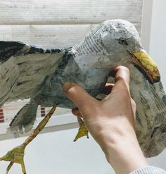 a person holding a bird made out of newspaper