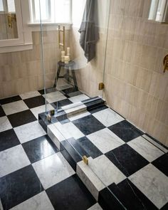 a black and white checkered floor in a bathroom with glass shower door, window, and towel rack