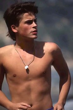 a shirtless young man standing on the beach