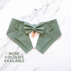 a green bow tie on top of a white marble surface with the words more colours available