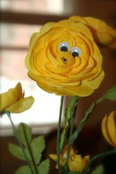 yellow flowers with googly eyes in a vase