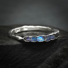 "Raw Uncut Rainbow Moonstone Band Ring // Silver Gold Raw Rough Uncut Organic Rustic Blue Flash Unique Rainbow Moonstone Wedding Band Ring This listing is for one raw natural Rainbow Moonstone band stone ring. Pictured ring is in sterling silver with dark base. DETAILS:  Stone: natural raw Rainbow Moonstone, dark metal base Metal:  - 925 silver  - 925 oxidise black (will start wearing lighter/off immediately) - 14k yellow, rose and white gold - 18k yellow gold Band width: approx. 2x1mm, hammered Fusion Style Wedding Ring With Birthstone, Unique Stackable Moonstone Ring For Wedding, Unique Stackable Moonstone Wedding Ring, Spiritual Stackable Moonstone Wedding Ring, Blue Fusion Style Wedding Rings, Fusion Style Moonstone Gemstone Ring For Anniversary, Fusion Style Anniversary Moonstone Gemstone Ring, Anniversary Fusion Style Moonstone Gemstone Ring, Wedding Sapphire Ring With Stones In Silver