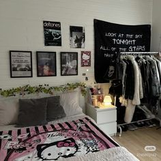 a bedroom with hello kitty pictures on the wall and clothes hanging up in front of it