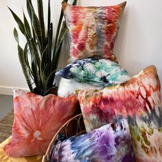 four colorful pillows on a table next to a potted plant