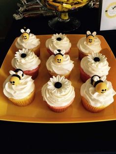 cupcakes with white frosting and yellow decorations on a plate next to bananas