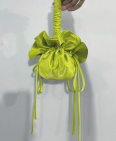 a hand is holding a yellow bag with a long tie on the handle and it has a knot at the top