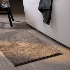 a bath room with a rug on the floor and a towel hanging from the wall