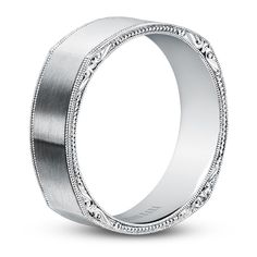 a white gold wedding band with intricate engraving on the sides and an engraved design in the middle