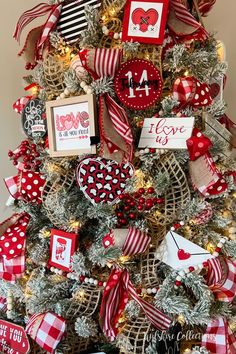 a christmas tree decorated with red and white ribbon, ornaments and pictures on it's branches