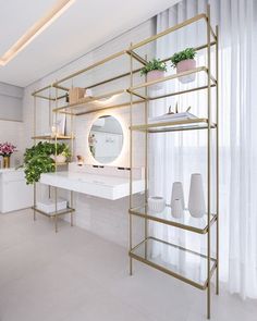 a white and gold bathroom with plants on the shelves