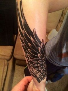 a person with a black and white tattoo on their arm that has an angel wing