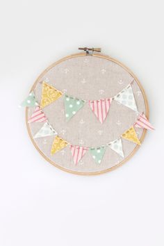 a cross - stitch pattern with bunting flags on it, hanging from a hoop