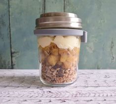 a glass jar filled with food sitting on top of a white table next to a wooden wall