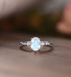 a ring with a white stone and three diamonds on it sitting on a wooden surface