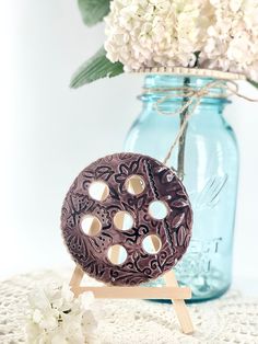 a vase filled with white flowers next to a wooden stand holding a chocolate donut