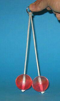 a hand holding two red glass balls on a white string with one hanging from it's end