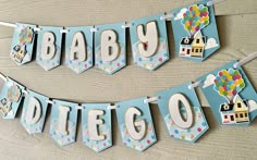 a banner that says baby due with balloons in the sky and clouds above it, on a wooden table